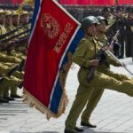 North Korean Troop Deployment to Russia: Implications for Ukraine Conflict and Global Alliances Soldiers marching with flag in military parade.