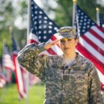 Saluting soldier in uniform with American flags background.