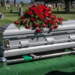 Silver casket with rose bouquet in a cemetery.