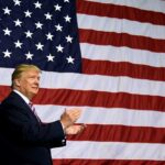 Man clapping in front of the American flag.
