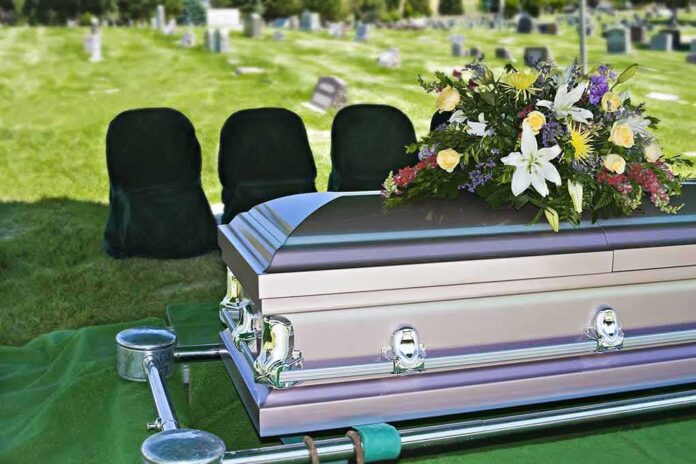 37139536 featured image Casket with floral arrangement in a cemetery.