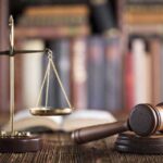 Gavel and scales on desk with books.