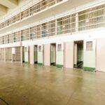 Empty prison cells with open doors, two-story layout.
