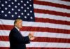Man clapping in front of American flag backdrop