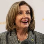 Smiling woman in plaid blazer with pearl necklace.