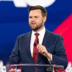 Man in suit speaking at a podium.