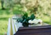 People placing white roses on a casket.