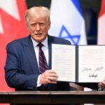 Man holding signed document with flags in background