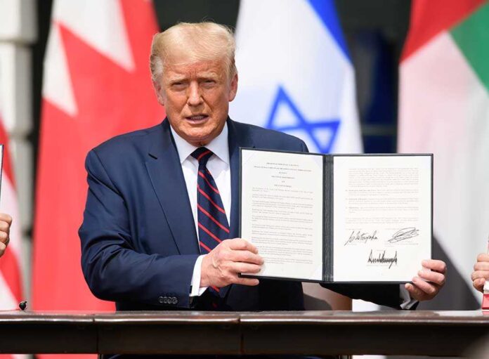 1816392461 featured image Man holding signed document with flags in background