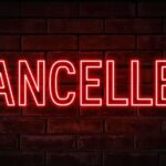 Red neon cancelled sign on brick wall background