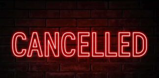Red neon cancelled sign on brick wall background