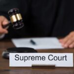 Judge with gavel and Supreme Court nameplate.
