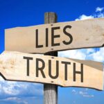 Signs pointing to "Lies" and "Truth" against sky.