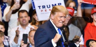 Man gesturing at rally surrounded by supporters