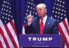 Person speaking at podium with American flags behind
