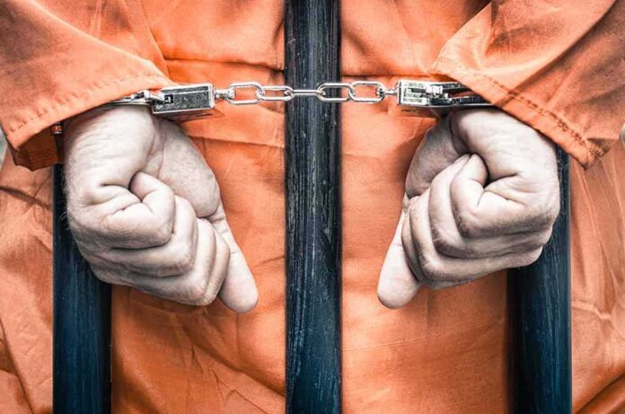 217094626 featured image Hands cuffed behind bars in prison uniform