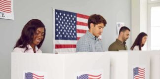 People voting in booths with American flag backdrop