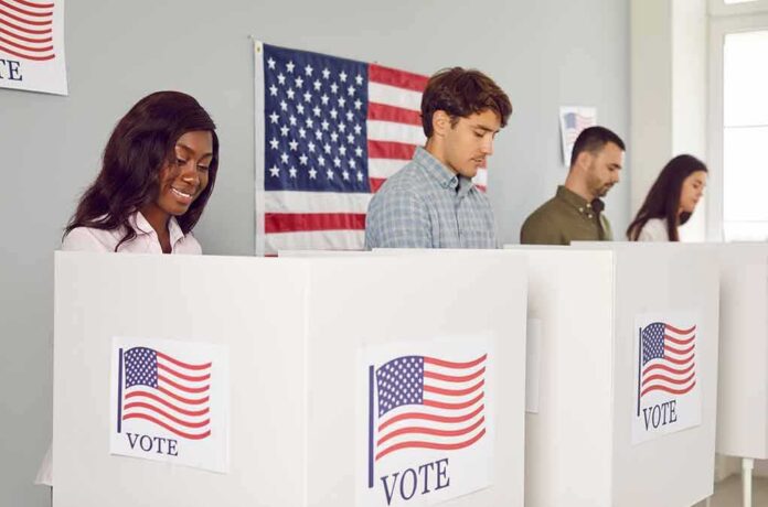 2360884499 featured image People voting in booths with American flag backdrop