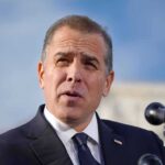 Man in suit speaking at a microphone podium.