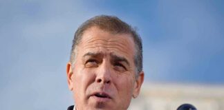 Man in suit speaking at a microphone podium.