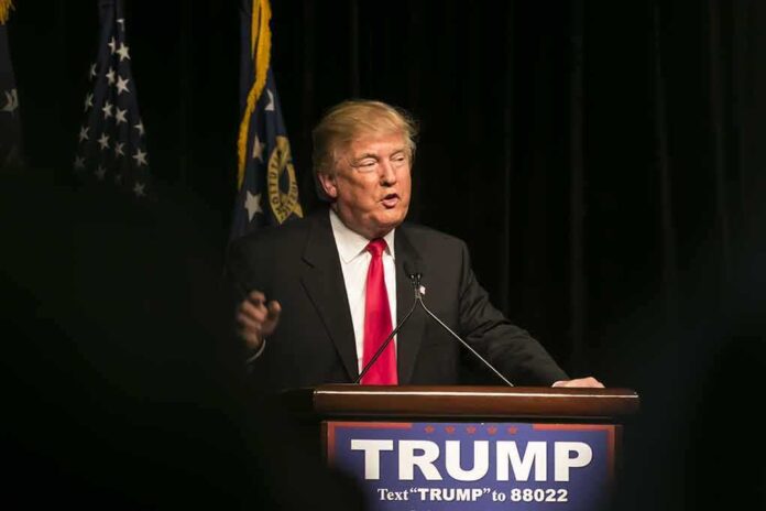 Man speaking at podium with flags in background