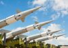 Multiple missiles pointed upward on launchers against blue sky