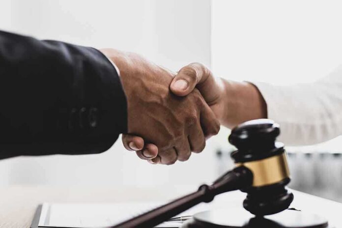 1789915493 featured image Handshaking near a gavel on desk.