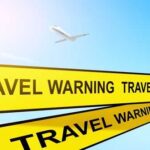 Airplane flying above travel warning signs sky background