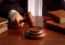 A judge's hand holding a gavel over a wooden desk with law books