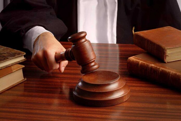 A judge's hand holding a gavel over a wooden desk with law books