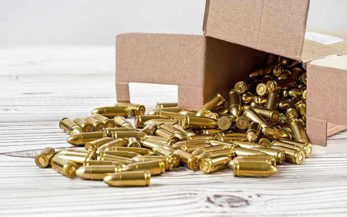 Box of brass bullets spilled on wooden surface