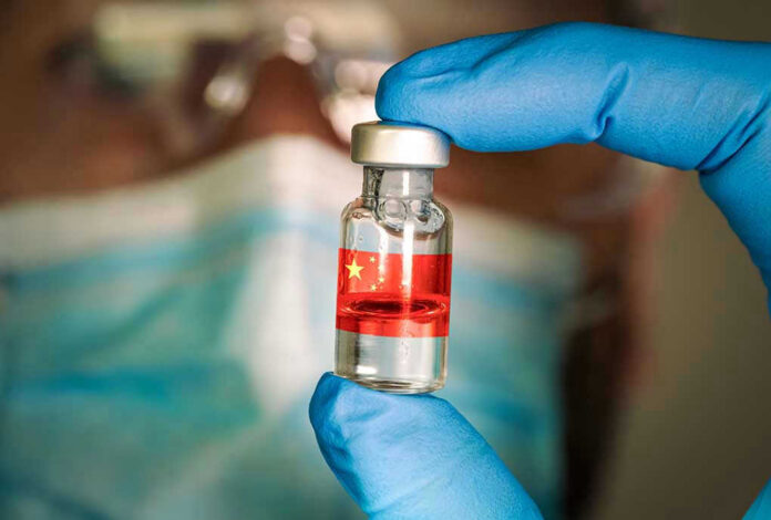 Gloved hand holding vial with red liquid and flag.