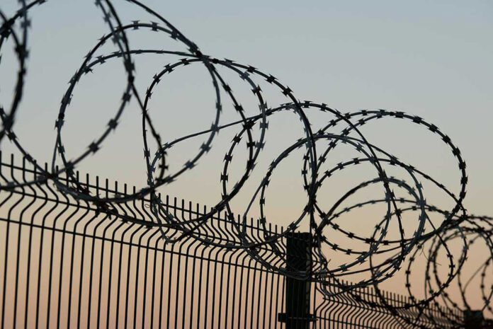 Barbed wire fence against sunset sky background