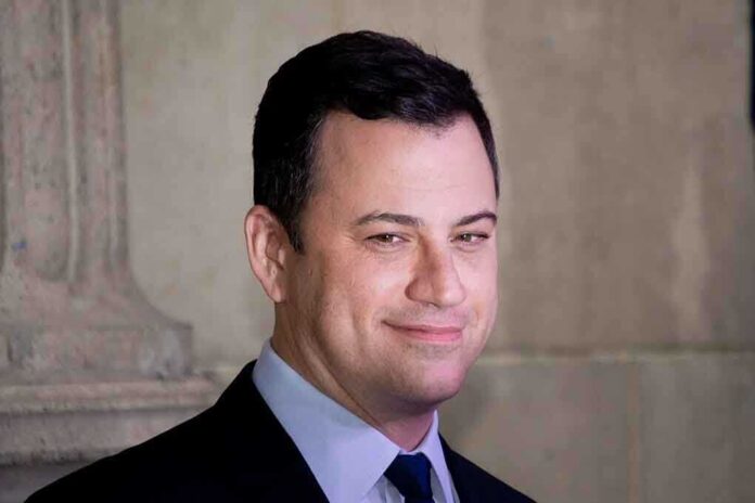 A smiling man in a suit with a confident expression against a neutral background