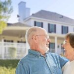 Elderly couple smiling and enjoying each other's company in front of a house
