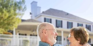Elderly couple smiling and enjoying each other's company in front of a house