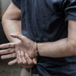 Person in handcuffs with hands behind back.
