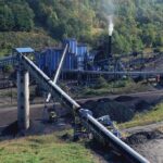 Industrial coal processing facility with conveyor belts and smoke stack