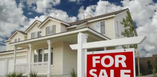 A suburban house with a For Sale sign in the front yard