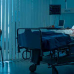 Woman sitting beside hospital bed at night