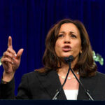Woman speaking passionately at a podium gesturing upward