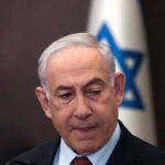 Man in suit with Israeli flag in background