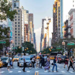 Busy city street with pedestrians cars and tall buildings