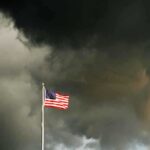 American flag waving against a dark stormy sky