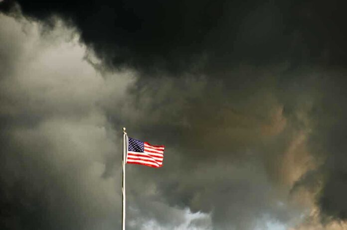 American flag waving against a dark stormy sky