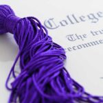 Close up of a purple graduation tassel next to a diploma