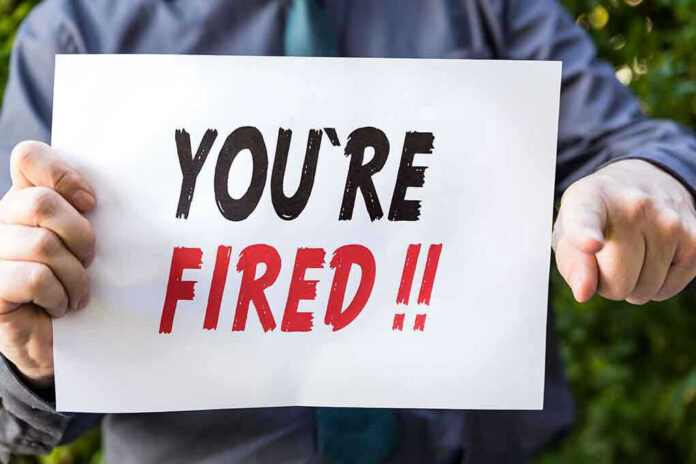 Person holding YOURE FIRED sign.