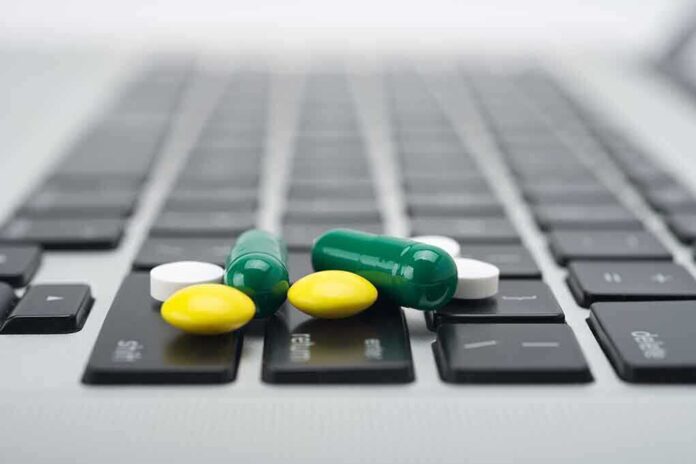 Various colored pills scattered on a laptop keyboard