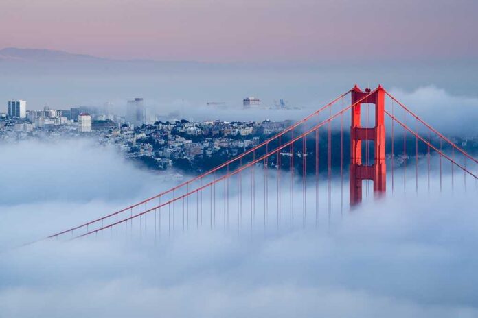 Golden Gate Bridge emerging from fog with San Francisco in the background