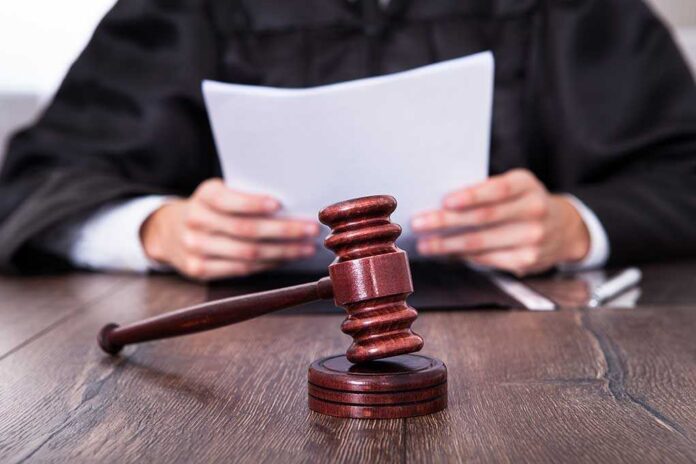A judge holding documents with a gavel in the foreground
